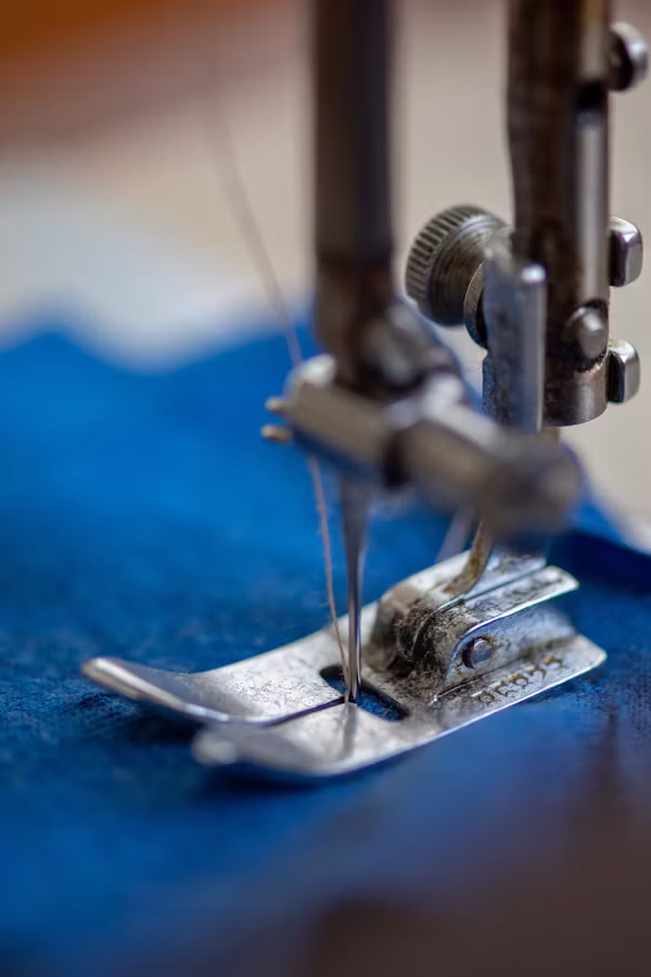 Primer plano del prensatelas cosiendo una tela azul